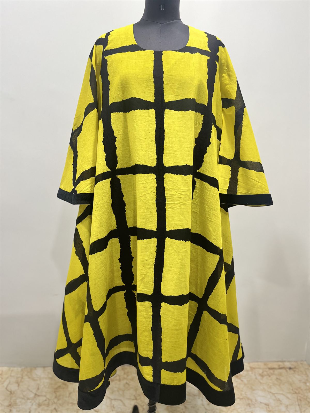 Yellow flared dress with a bold black grid print and black hem